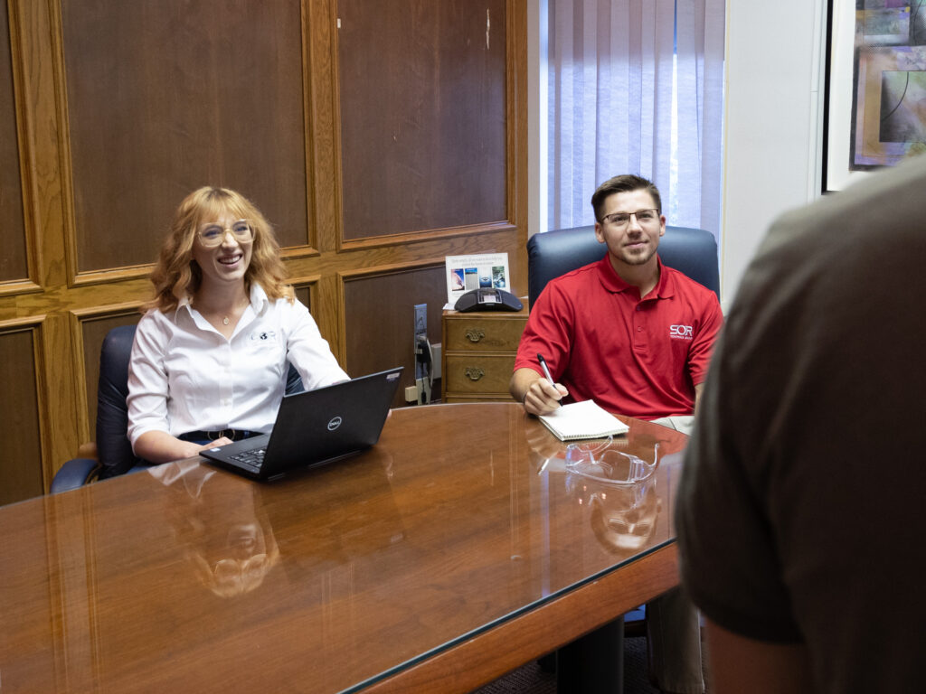 Smiling SOR employees working at a conference table